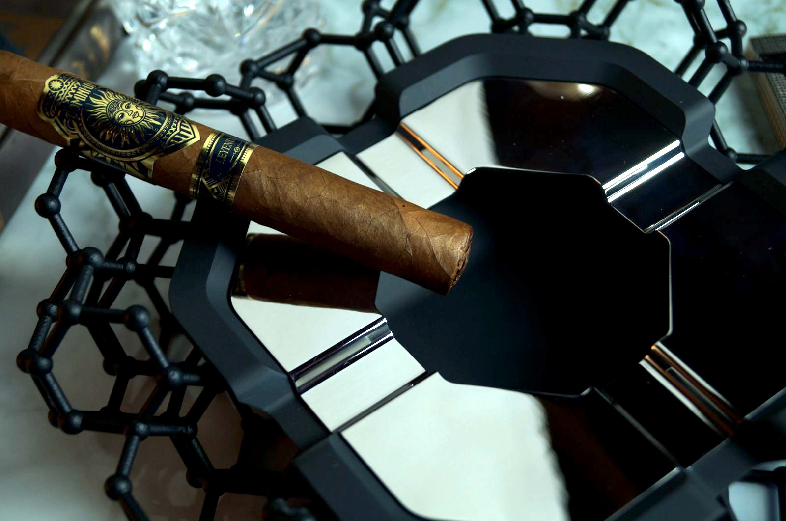A Dominium Leyenda cigar resting on a modern black and chrome ashtray